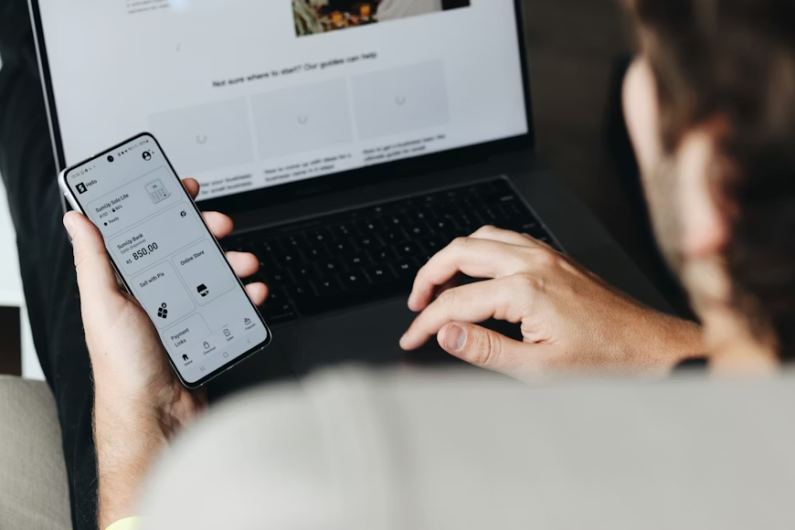 ソファに座ってノートパソコンを使う男性